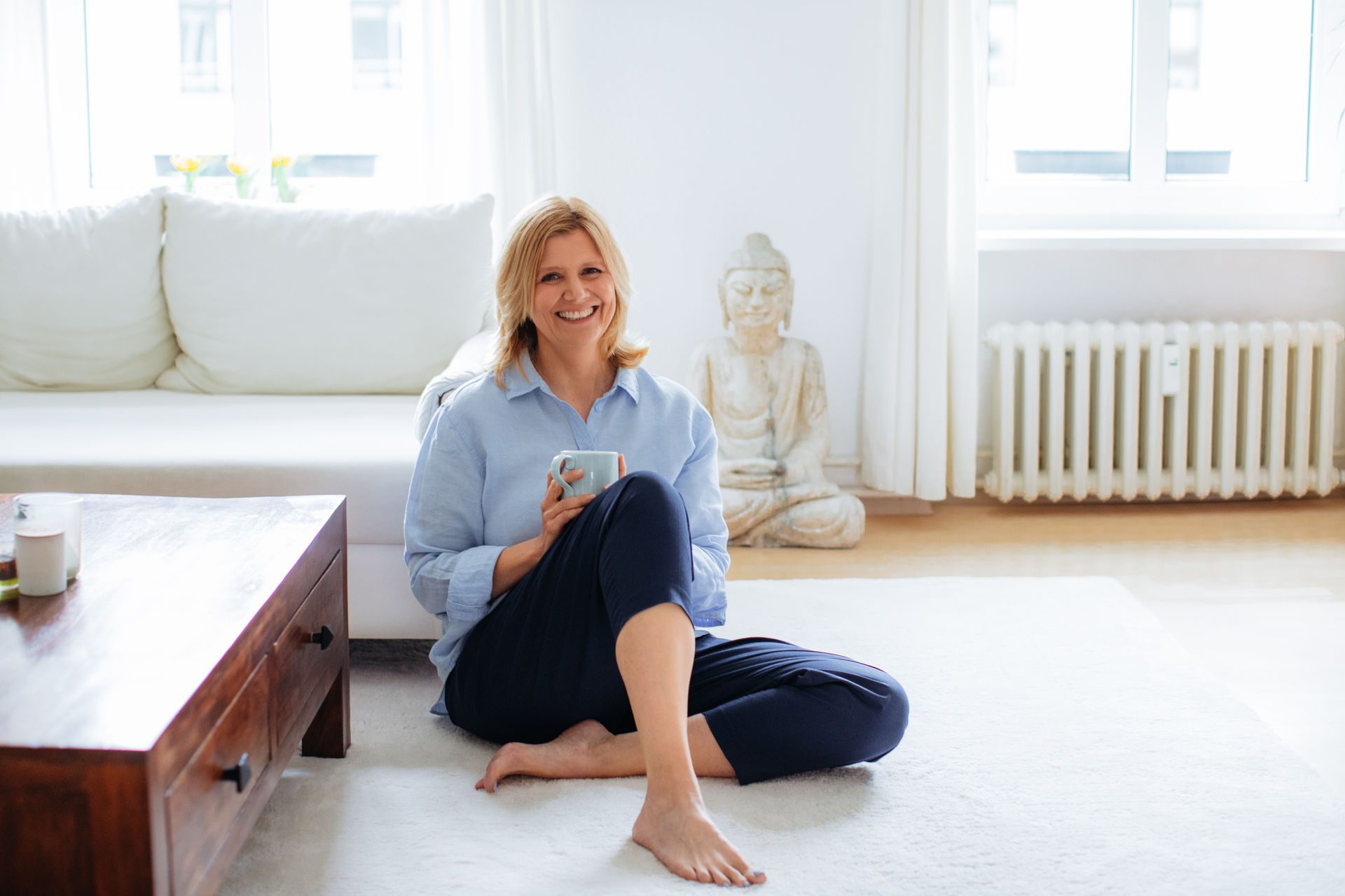 Ines Gerecht sitzt mit einer Tasse in der Hand auf dem Boden